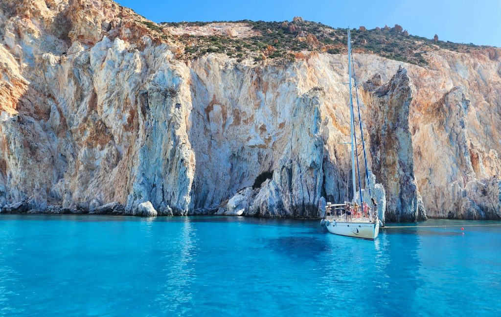 A boat floating in a body of water next to a mountain